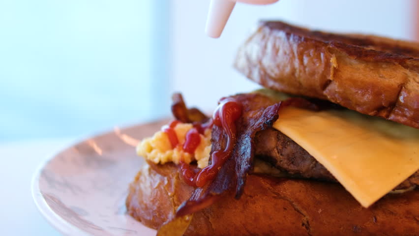 pour a lot of ketchup and mayonnaise cook is pouring ketchup on a burger bun. Close shot 