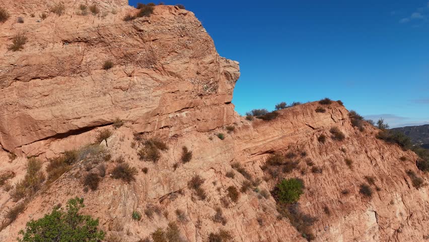 Drone view of dramatic sandstone formations in Black Star Canyon, California, highlighting the rugged, arid terrain and distinct layers of exposed rock under clear blue skies