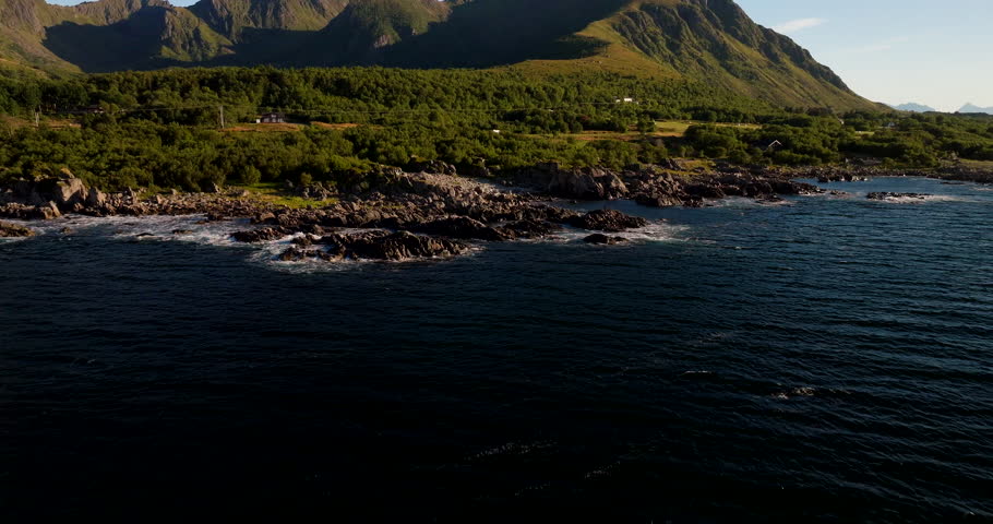 Uværshula, beautiful coastal landscape in Vesterålen, rocky shore, green mountains, and arctic ocean in northern Norway. Aerial backward, copy space