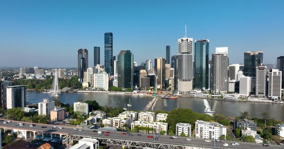4K aerial left to right pan tracking view of the iconic Story Bridge and east side of Brisbane CBD with Brisbane River below where CityCat ferries commute passengers, Brisbane, Queensland, Australia