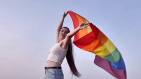 A euphoric woman raises the Rainbow Flag high against a vast, open sky. This moment symbolizes LGBTQ freedom, self-love, and the spirit of community pride - Powered by Shutterstock - Get 15% off with code: PIKWIZARD15