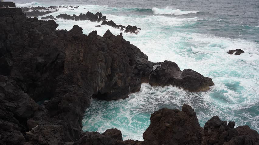 Waves crashing against black rocks in Porto Moniz in Madeira, Portugal