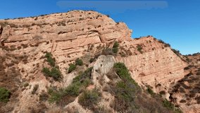 Close-up drone shot of layered sandstone cliffs in Black Star Canyon, California, featuring detailed erosion patterns, sunlit rock textures, and sparse desert vegetation under a vibrant blue sky - Powered by Shutterstock - Get 15% off with code: PIKWIZARD15