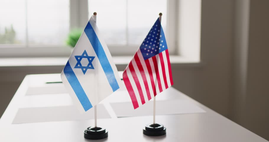 Flags signal diplomacy and negotiation at meeting. Desk flags of Israel and the United States on a conference table suggest formal ties and talks. Symbol of bilateral dialogue and partnership.