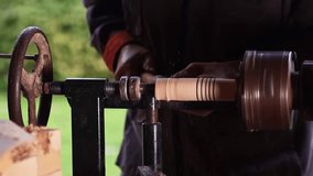Close-up of a craftsman shaping wood on a spinning lathe outdoors. Detailed view of traditional woodworking using hand tools and classic belt-driven machinery. - Powered by Shutterstock - Get 15% off with code: PIKWIZARD15