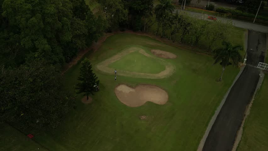 4K drone aerial of a lush green golf course surrounded by tropical hills and dense trees — perfect for resort and leisure promos