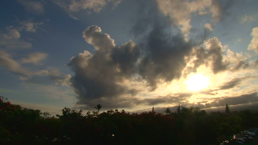 Sun shines through clouds in Hawaii during sunrise, time lapse.