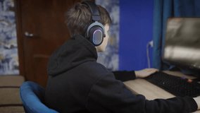 Teenage boy in headset playing online first person shooter game on personal computer in room in apartment - Powered by Shutterstock - Get 15% off with code: PIKWIZARD15