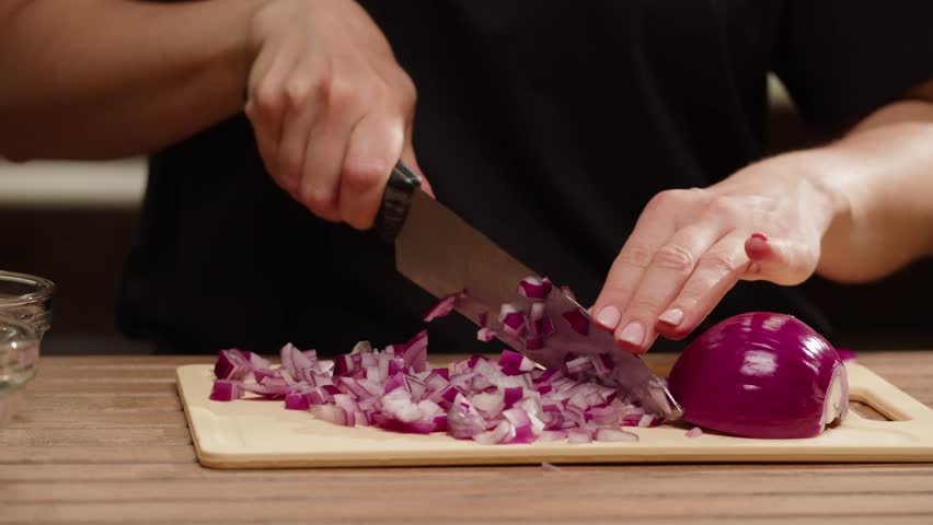 Woman is cutting red onions into slices on a cutting board