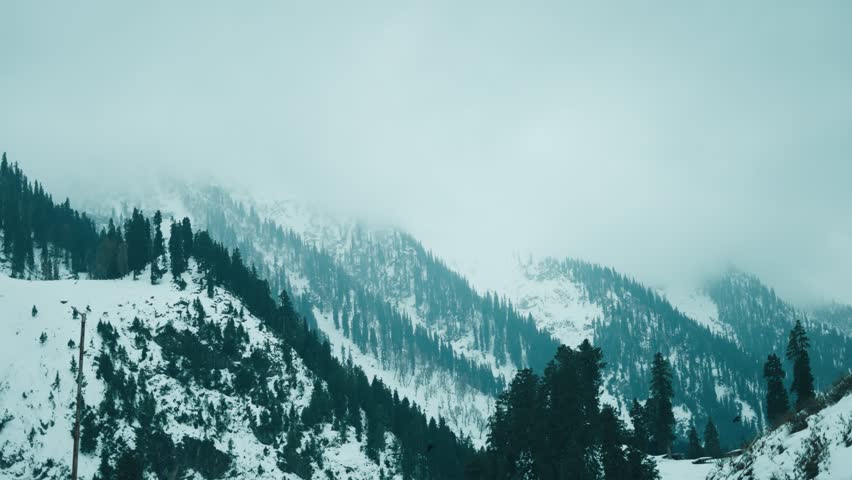 Beautiful view of white snowy mountain range with cloudy sky during cold winter. Nature concept. Mountains and pine forest covered with snow at Chandanwari, Jammu and Kashmir, India. Winter landscape.