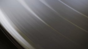 Close-up view of a black vinyl record spinning on a turntable. The grooves reflect light, creating a hypnotic and classic visual - Powered by Shutterstock - Get 15% off with code: PIKWIZARD15