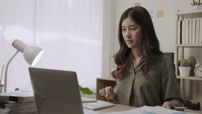 Professional young Asian female business accountant sitting using a calculator and a laptop computer for analyzing financial data at her desk in the office. Businesswoman working in her workplace.  - Powered by Shutterstock - Get 15% off with code: PIKWIZARD15