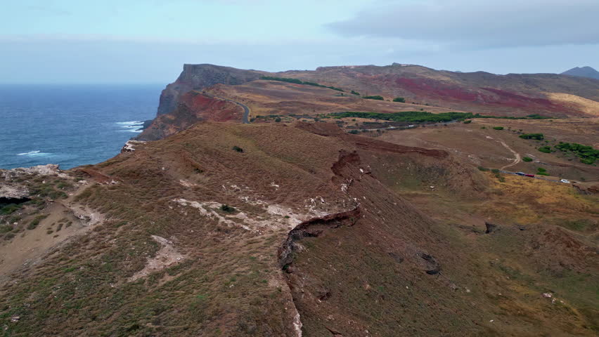 Cliff edge stretching coastline with rough stone formations surrounded by sea water. Aerial view natural shoreline landscape under cloudy sky. Scenic ocean splashing on rocky coast rolling with foam