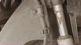 A close-up shot of a mechanic using a tool (possibly a cutter or sharp scraper) to clean dirt, grime, or rust buildup from the shiny chrome shaft of a motorcycle's front shock absorber - Powered by Shutterstock - Get 15% off with code: PIKWIZARD15