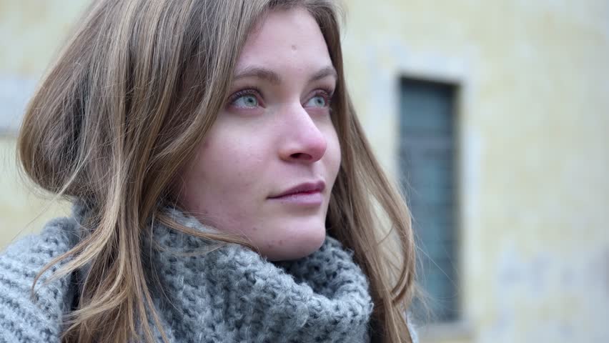 In a moment of solitude, the profile of a young blonde woman draped in a scarf reflects a poignant sadness, her gaze lost in contemplation.