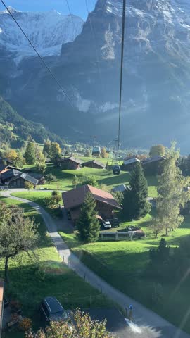 watching autumn alps village from cable car with snow capped mountain in the background, Grindelwald in Switzerland, snow capped