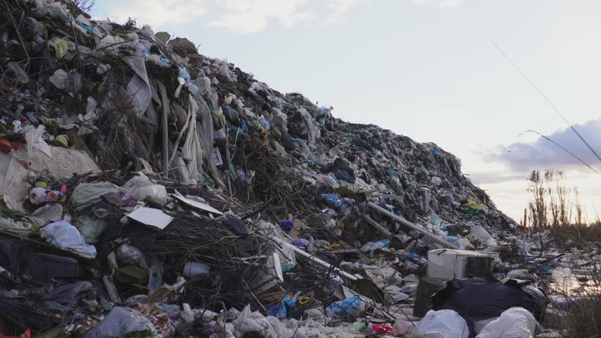 Large pile of garbage and debris in a landfill at sunset.