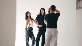 Professional photographer capturing stylized portrait session with two female models posing against crisp white studio background during collaborative fashion photography shoot - Powered by Shutterstock - Get 15% off with code: PIKWIZARD15