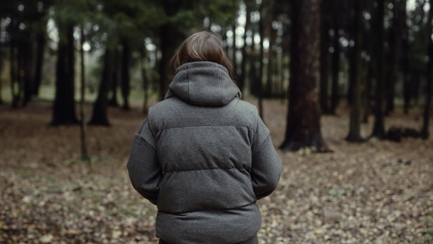 Woman turning around and running away through autumn forest, back view