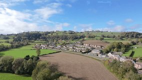 Aerial drone video of a small Welsh village near Ruthin, Denbighshire. Rolling green hills, plowed fields, church, red bus on road. Sunny day, blue sky. - Powered by Shutterstock - Get 15% off with code: PIKWIZARD15