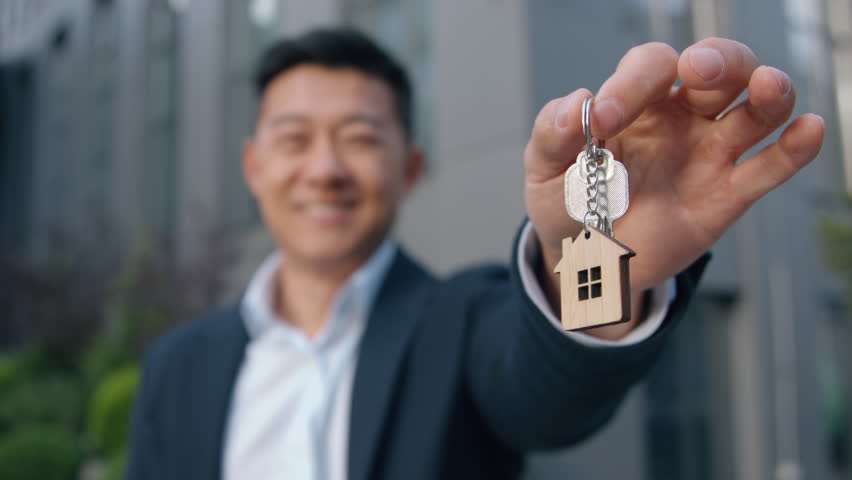 Happy Asian business man showing bunch of keys businessman Chinese male developer relocation dealer property home mortgage loan insurance ownership buy house Japanese trader real estate agent in city