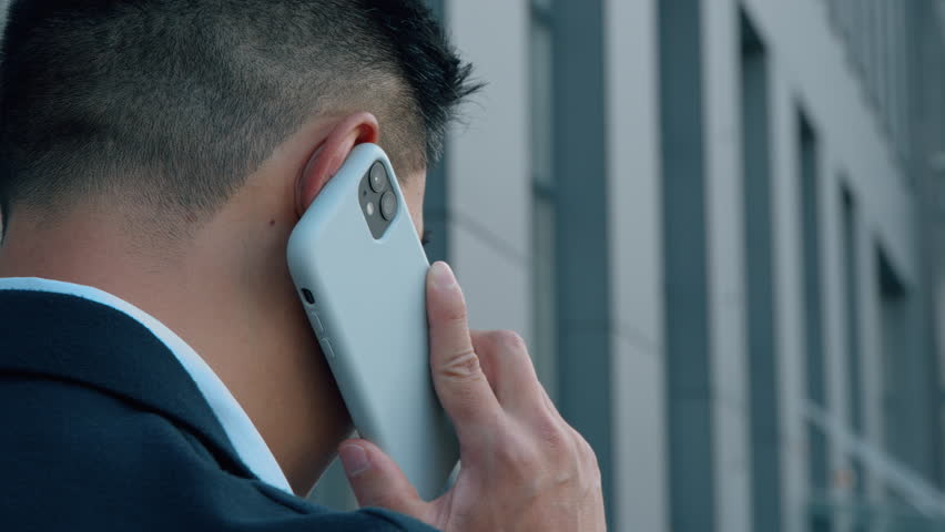 Back view unrecognizable Asian business man talking mobile phone businessman talk smartphone call communicate formal corporate negotiation unknown male conversation in city negotiate work job discuss