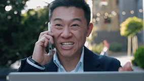 Happy smiling Asian business man talking mobile phone laptop using looking computer screen Korean businessman in city talk speaking smartphone call Chinese Japanese male communicate conversation work - Powered by Shutterstock - Get 15% off with code: PIKWIZARD15