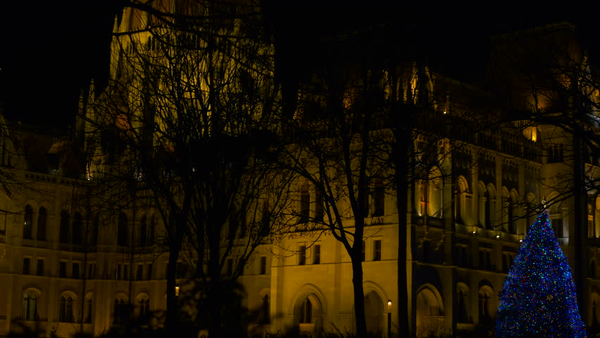 Hungarian parliament building at night with christmas tree. Warm lights illuminate the hungarian parliament building in budapest at night, with a decorated christmas tree, creating a magical scene