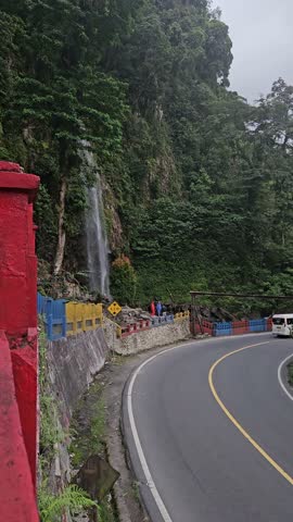 A rapid river with strong currents flows over and around large rocks, creating white water and a small cascade, surrounded by a green.