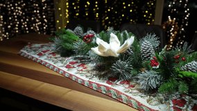 A beautifully decorated table runner with pinecones, greenery, and a white flower creates a warm holiday atmosphere - Powered by Shutterstock - Get 15% off with code: PIKWIZARD15
