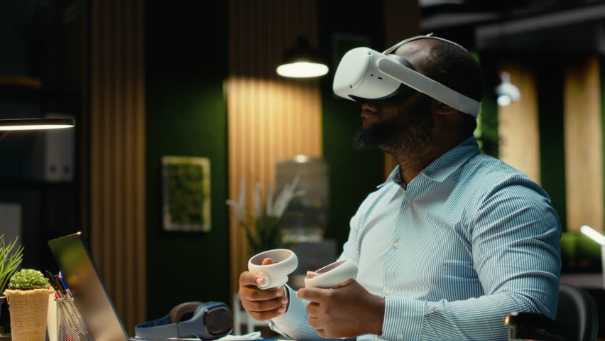 African american employee using AI tools with virtual reality late at night, working hard in the office with VR glasses to ensure fact checking and forecasting projections. Strategy room. Camera B. - Powered by Shutterstock - Get 15% off with code: PIKWIZARD15