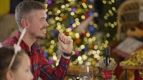 A man in a red plaid shirt smiles while celebrating Christmas with his family, enjoying the holiday spirit - Powered by Shutterstock - Get 15% off with code: PIKWIZARD15