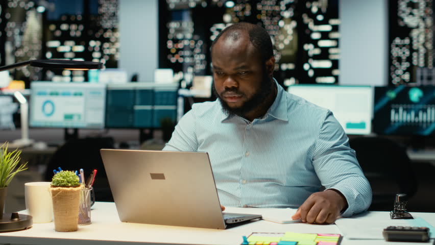 African american strategist ripping a paper after writing the wrong idea, restarting work in rage and crumpling the page sheet. Discontent man does a typo mistake while transcribing. Camera B.