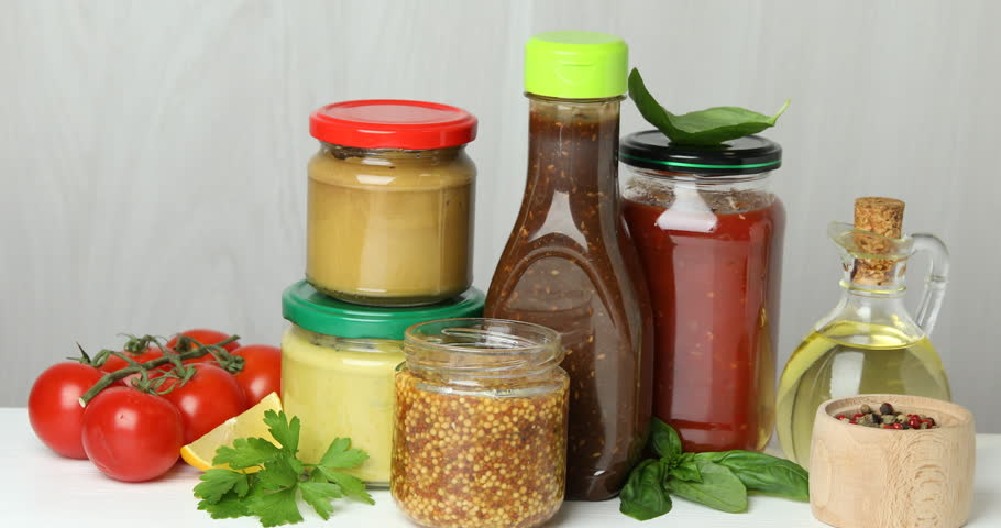 Woman with French mustard and other sauces at white table, closeup