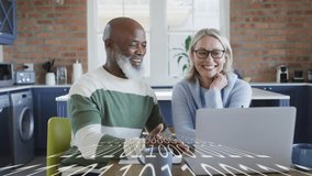 Couple sitting at kitchen table tapping laptop checkout, viewing animated icons to complete payment. Couple, collaboration, modern, lifestyle, technology, finance, connection - Powered by Shutterstock - Get 15% off with code: PIKWIZARD15