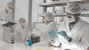 Medium long shot of diverse scientists in gowns, masks, and gloves working and discussing research in a bright laboratory.
 - Powered by Shutterstock - Get 15% off with code: PIKWIZARD15