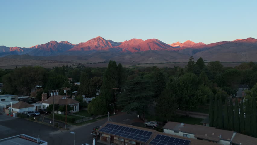 Aerial shot showcases vibrant mountain peaks at sunset, BIg Pine Lakes in california, framed by a charming town below. Natures beauty invites exploration and admiration from all who see it