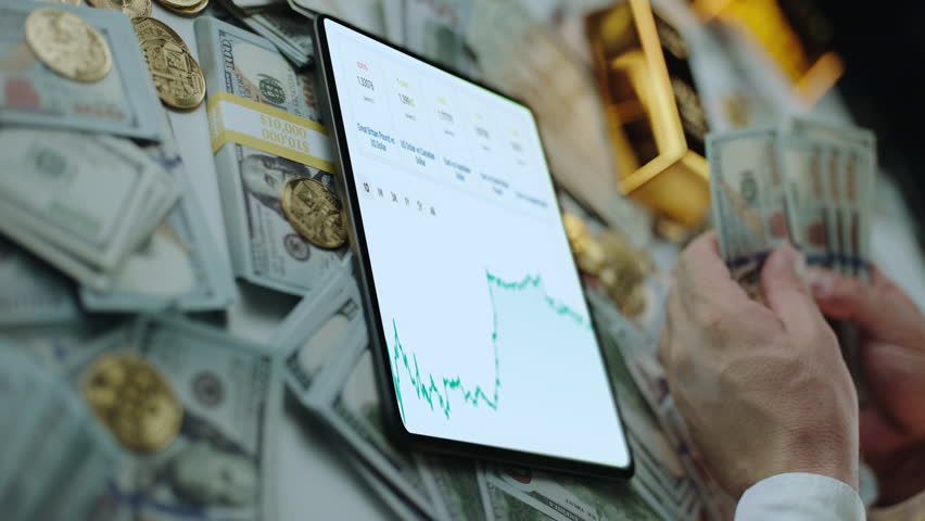 Tablet screen showing a financial stock market chart with a person counting dollar bills, gold coins, and bullion bars in the background, representing investment success and wealth accumulation