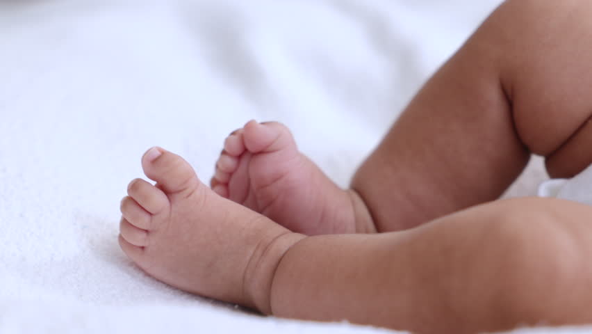 Close-up of newborn baby feet resting on soft white blanket, highlighting innocence, comfort, and gentle texture of fabric used in childcare, reflecting infant comfort, softness skincare for infants