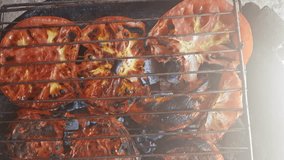 Tomato slices grilled over charcoal, their skins blistered and blackened in places. Smoke drifts between the slices, releasing a smoky sweetness and flavor - Powered by Shutterstock - Get 15% off with code: PIKWIZARD15