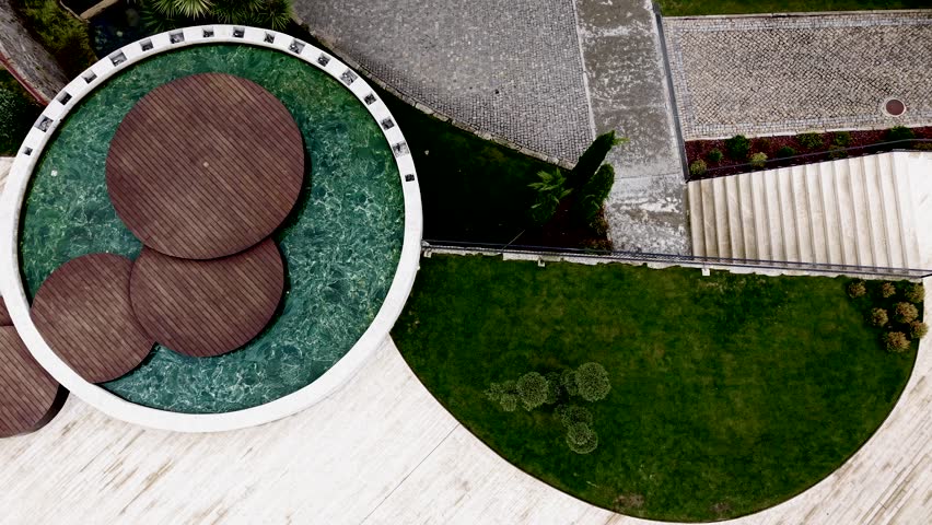 top view of circular wooden decks over water beside geometric garden lawn