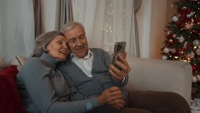 Aged spouses celebrating Christmas and New year, calling by mobile app from home . Portrait of happy elderly man and woman smiling to frontal camera of smartphone, online chatting and congratulating - Powered by Shutterstock - Get 15% off with code: PIKWIZARD15