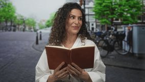 Woman reading book on busy city street with hands turning pages and an attentive expression; serenity reflection. - Powered by Shutterstock - Get 15% off with code: PIKWIZARD15