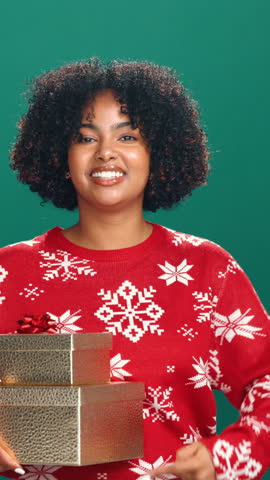 Christmas, face or black woman with present in studio, pointing or excited for festive shopping. Holiday season, person laugh or gift box for sale announcement, deal and discount on green background