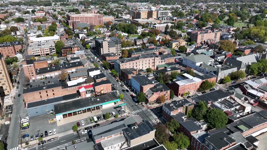Downtown Main Street with buildings during sunny Day in Lancaster, Pennsylvania. Aerial approaching wide shot. Cars between houses and homes in autumn season.