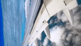 An airplane wing flies in a blue sky with beautiful cumulus clouds that periodically block the sun and a shadow briefly appears on the wing, Vertical video   - Powered by Shutterstock - Get 15% off with code: PIKWIZARD15