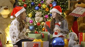 Two young girls wearing Santa hats open gifts on Christmas morning, filled with joy and excitement - Powered by Shutterstock - Get 15% off with code: PIKWIZARD15