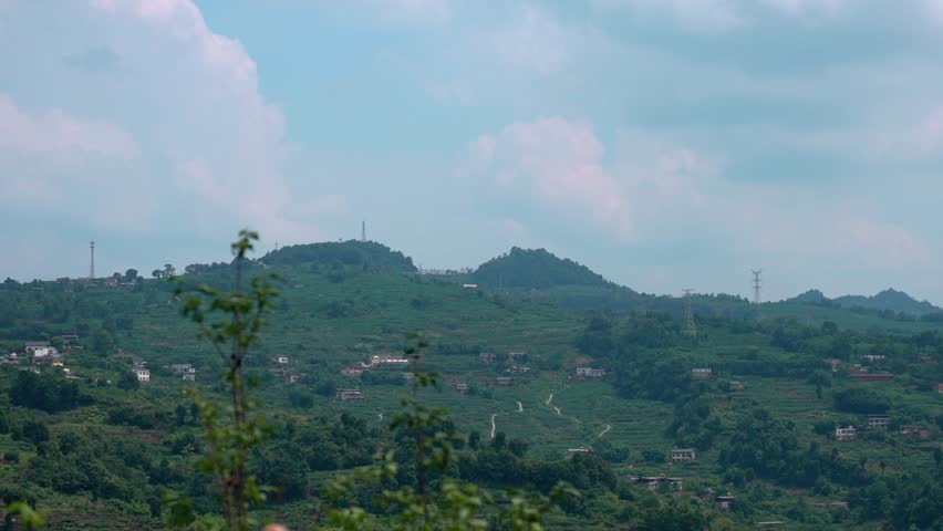 In the depths of the mountains, under the blue sky and white clouds, there are several households on the opposite side of the mountain.
