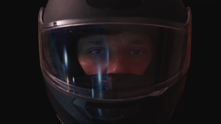 Man Riding and Lifting Helmet Visor While Giving Thumbs Up Gesture in Dark Environment, Close-Up Front View, Night Ride Concept.