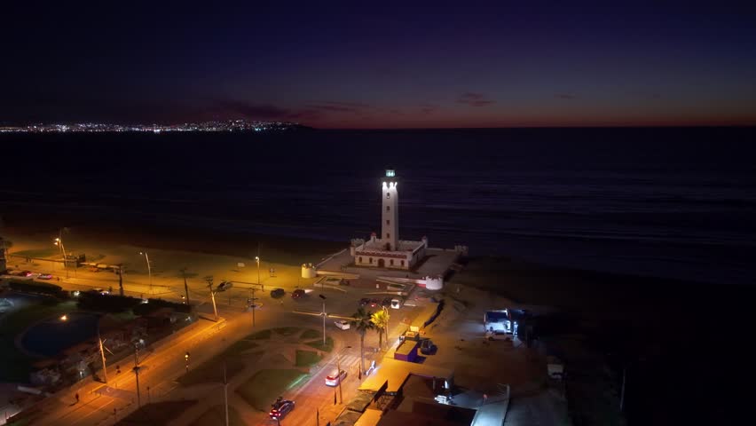 Evening view of Faro de La Serena, streets glowing with lights against a dark coastal horizon.